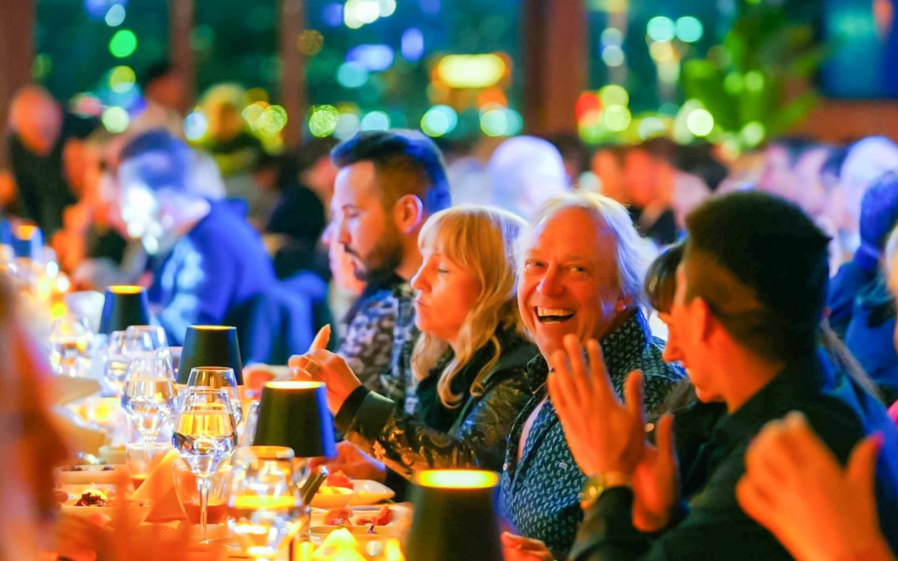 Guests enjoying dinner on a Bosphorus cruise, toasting with drinks.