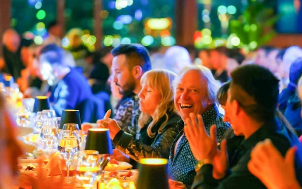 Guests enjoying dinner on a Bosphorus cruise, toasting with drinks.