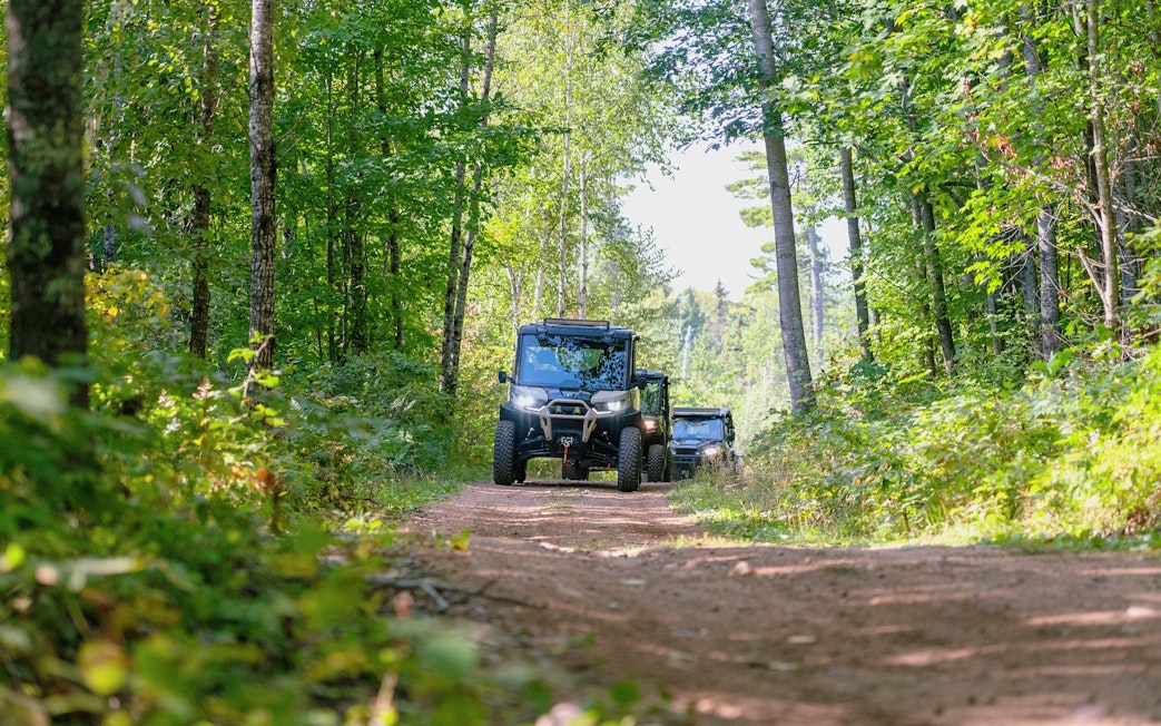 Friends driving ATVs and UTVs on a forest trail.