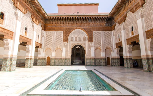 Ben Youssef Madrasa courtyard with intricate tilework and central pool in Marrakech, Morocco.