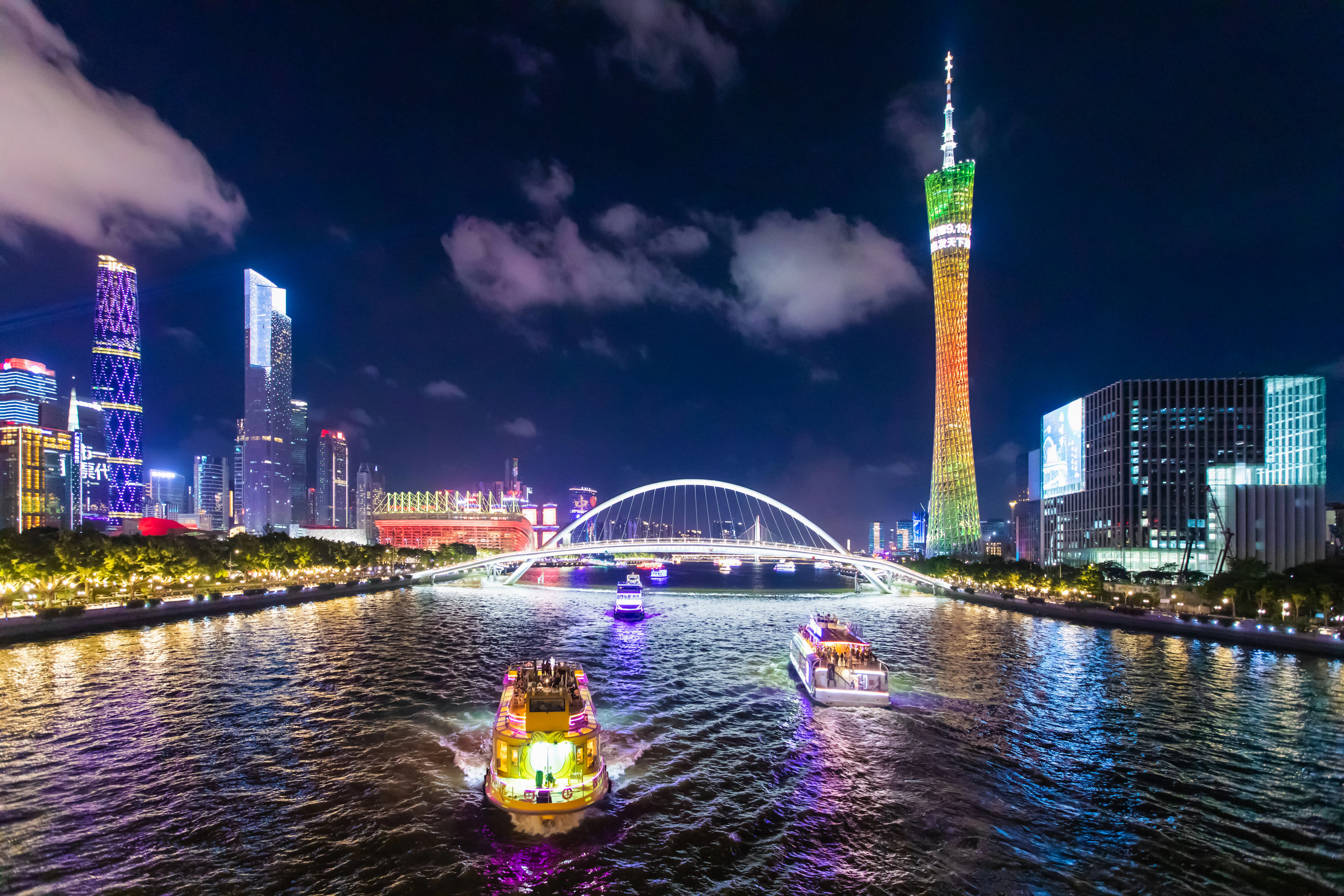 Pearl River night cruise with lit boats, Guangzhou skyline, and Canton Tower.