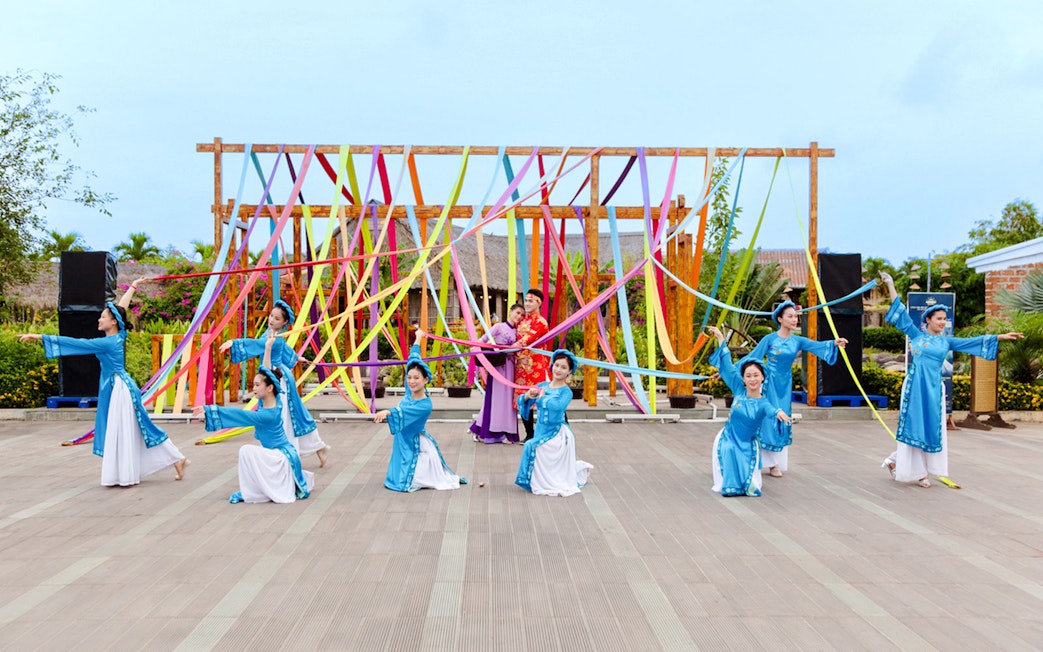 Performers in traditional costumes at Hoi An Memories Show, Vietnam, with colorful ribbons.