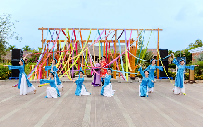 Performers in traditional costumes at Hoi An Memories Show, Vietnam, with colorful ribbons.