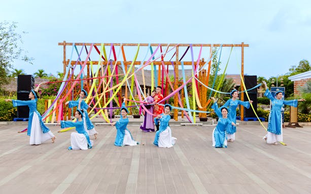 Performers in traditional costumes at Hoi An Memories Show, Vietnam, with colorful ribbons.