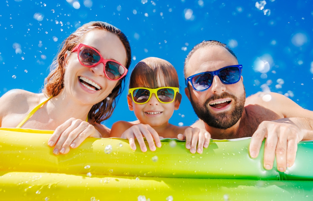 Family enjoying a waterpark on a sunny day with colorful float.