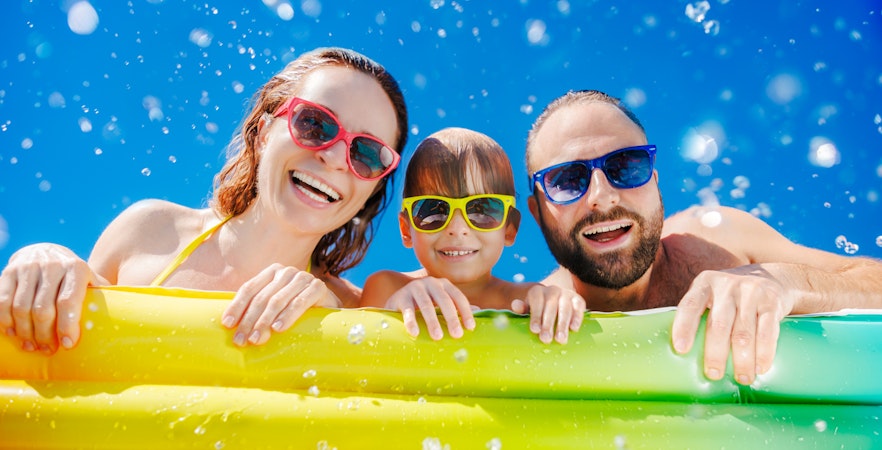 Family enjoying a waterpark on a sunny day with colorful float.