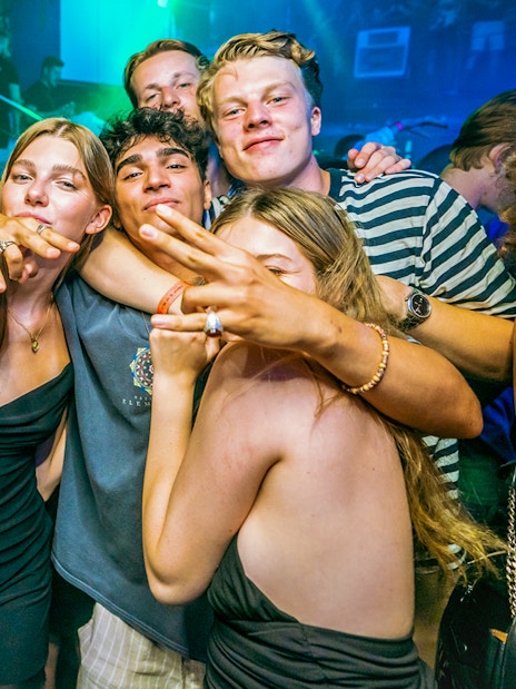 Group of people enjoying a lively boat party in Prague with vibrant lighting.