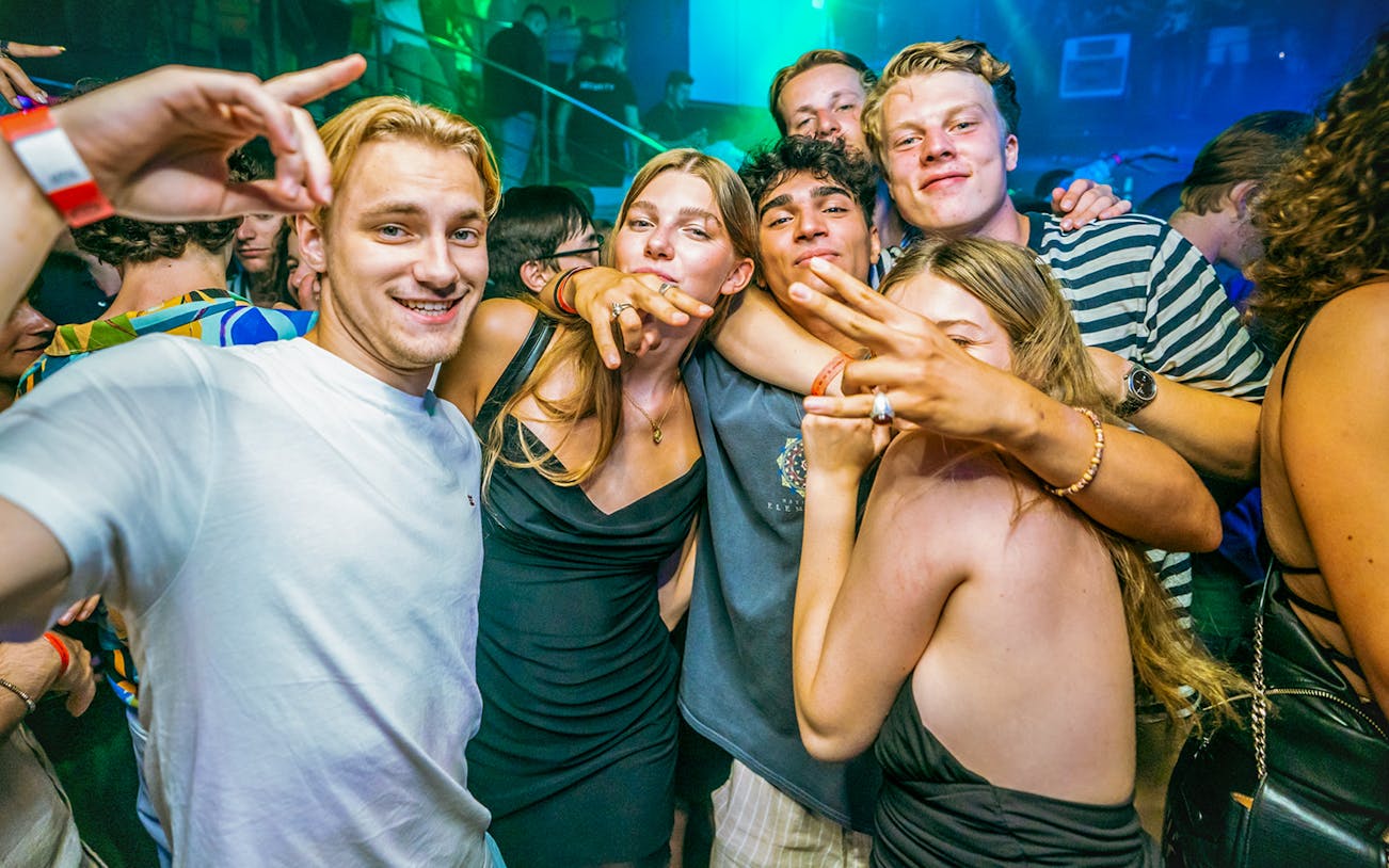 Group of people enjoying a lively boat party in Prague with vibrant lighting.