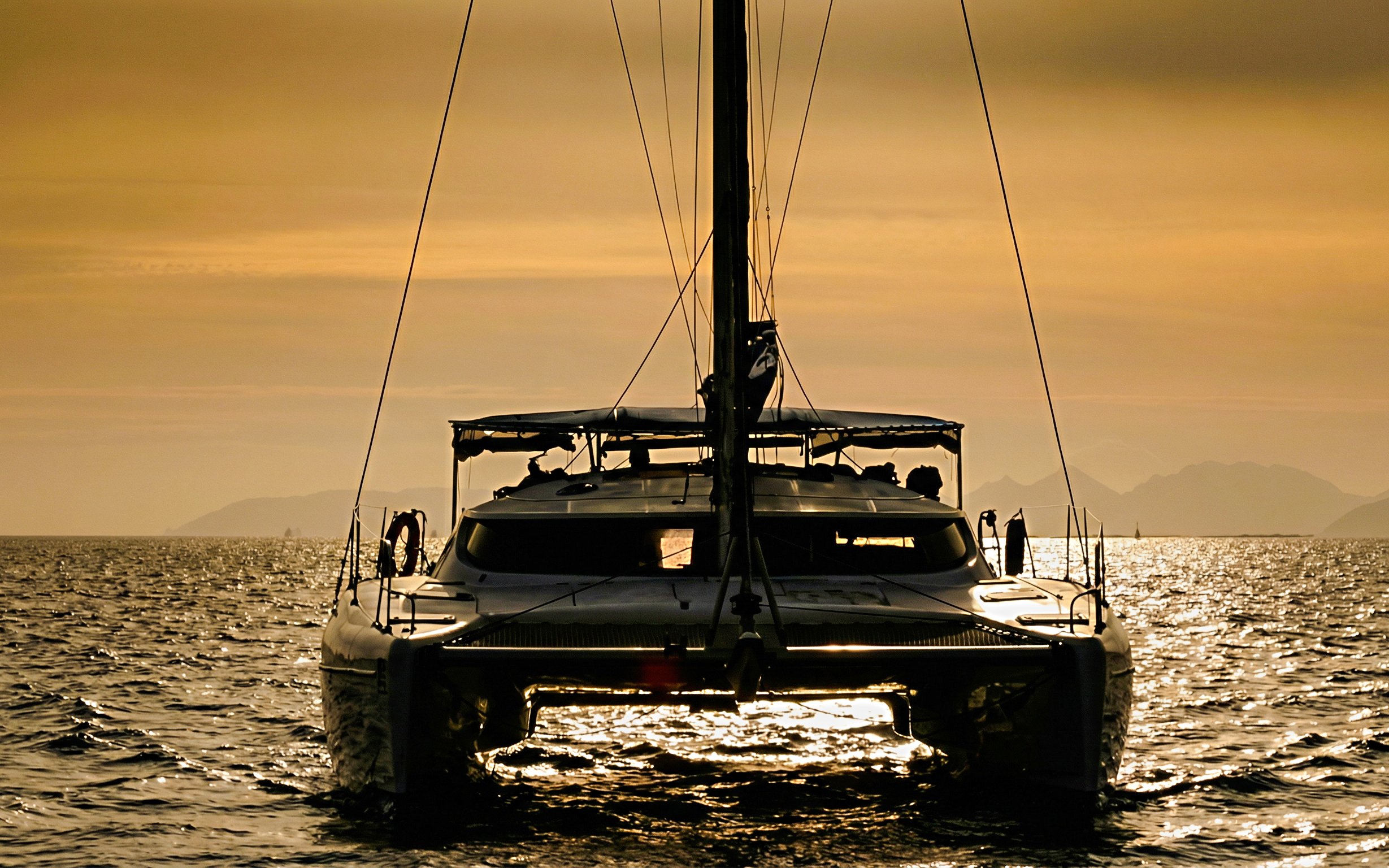 Catamaran sailing at sunset in La Maddalena Archipelago.