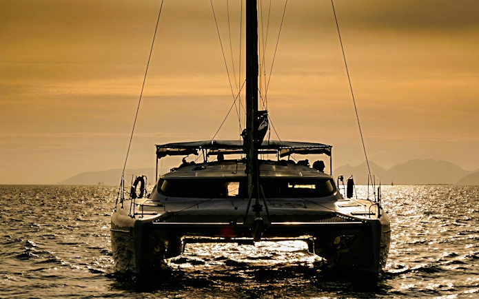 Catamaran sailing at sunset in La Maddalena Archipelago.