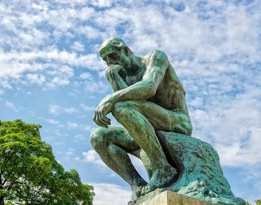 Rodin's The Thinker statue against a blue sky at The Muse.