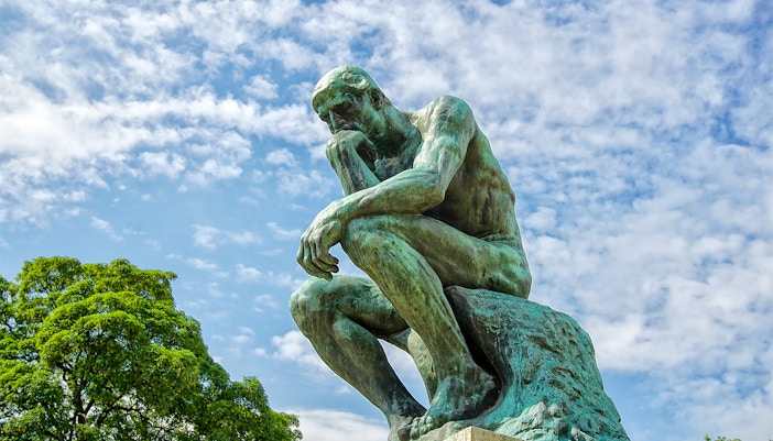 Rodin's The Thinker statue against a blue sky at The Muse.