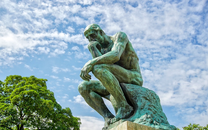 Rodin's The Thinker statue against a blue sky at The Muse.