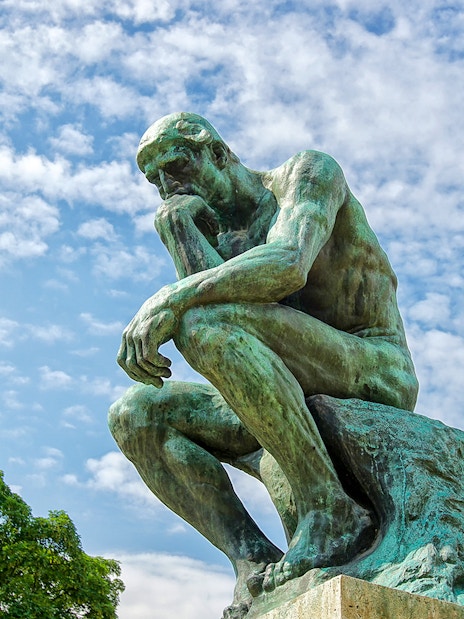 Rodin's The Thinker statue against a blue sky at The Muse.