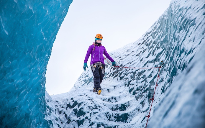 Hiker traversing icy terrain on Falljökull glacier in Iceland.
