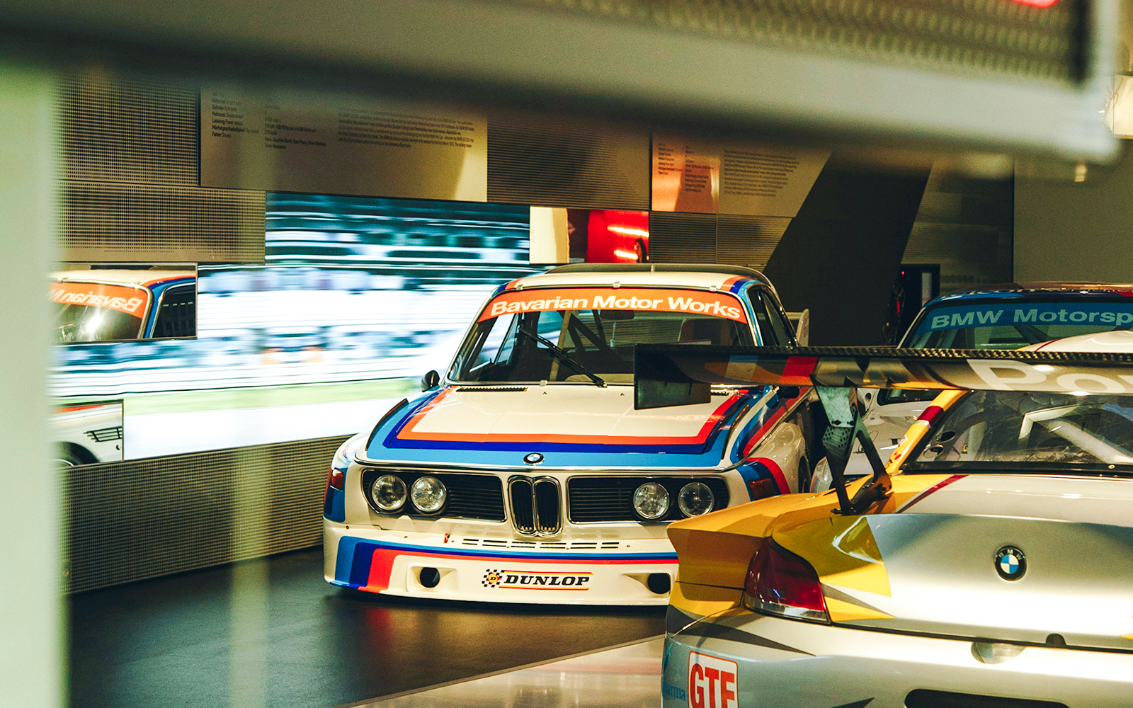 BMW race cars displayed at a museum exhibit.