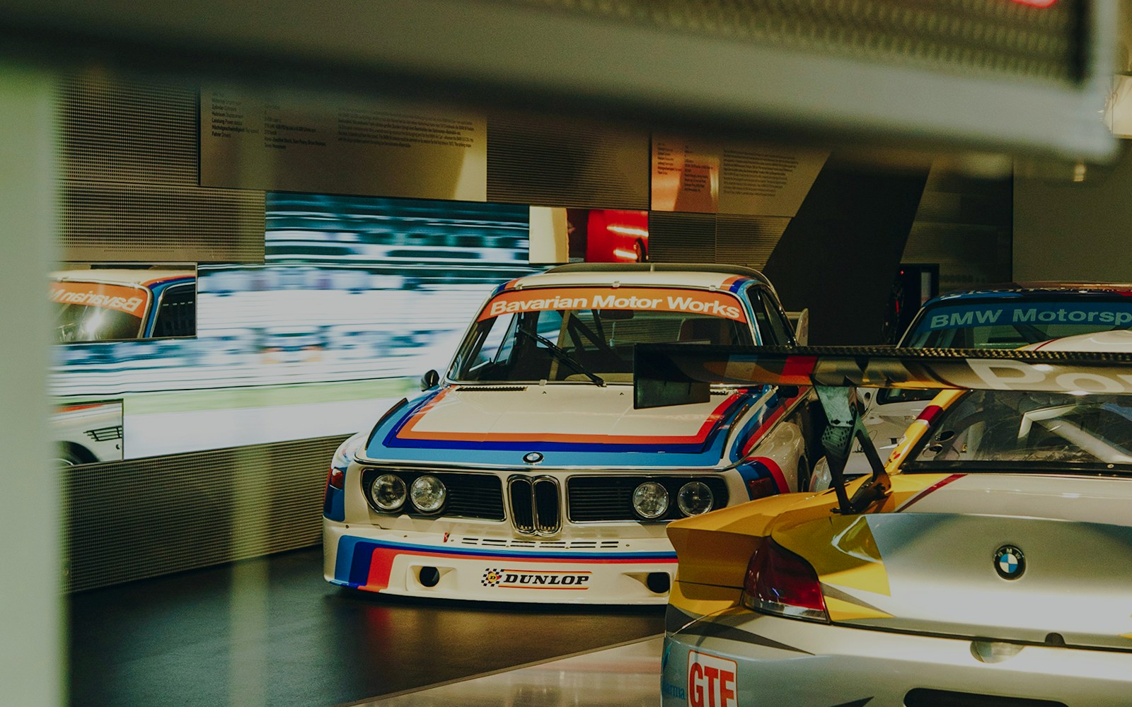 BMW race cars displayed at a museum exhibit.