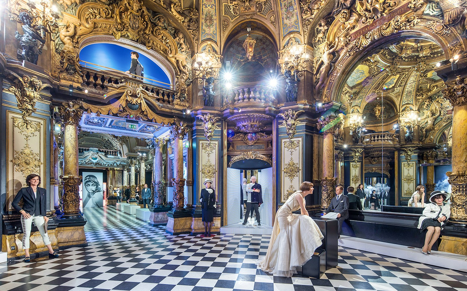 Grévin Paris wax museum interior with ornate decor and wax figures in elegant attire.