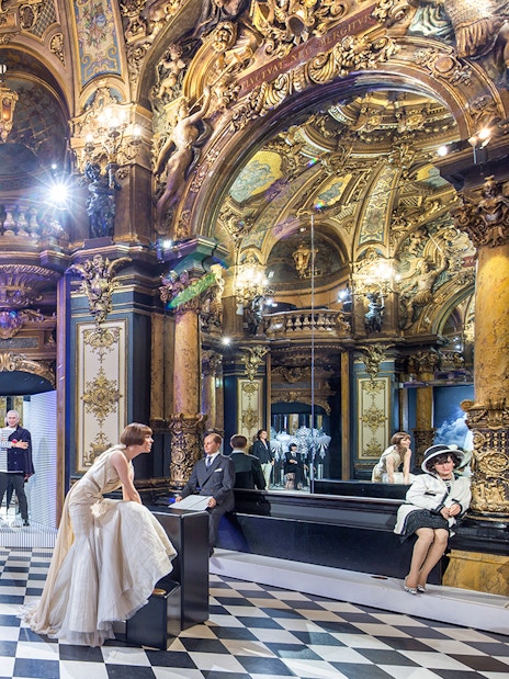 Grévin Paris wax museum interior with ornate decor and wax figures in elegant attire.
