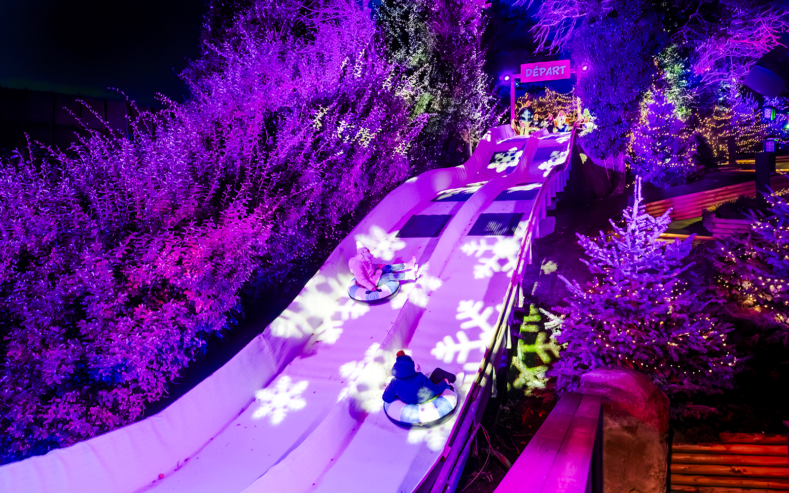 Family enjoying snow tubing at Parc Asterix during Christmas celebrations.