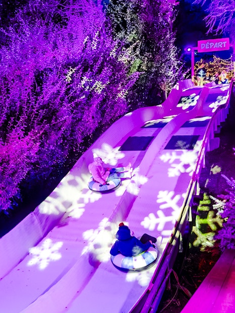 Family enjoying snow tubing at Parc Asterix during Christmas celebrations.