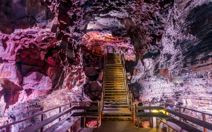 Staircase inside Raufarhólshellir Lava Tunnel with illuminated rock formations.