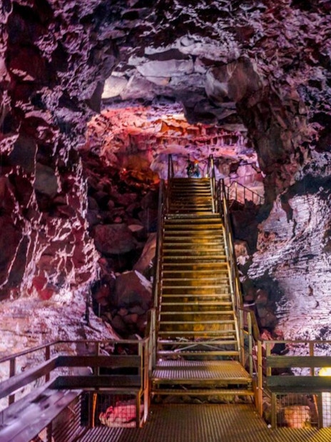 Staircase inside Raufarhólshellir Lava Tunnel with illuminated rock formations.
