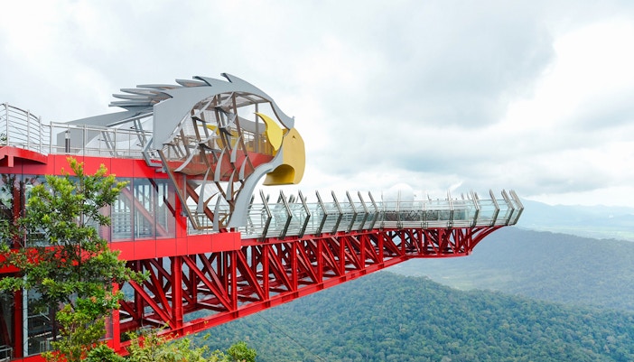 Langkawi Skywalk visitors on glass bridge with panoramic views of lush rainforest and mountains.