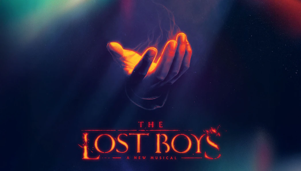 Hand with glowing light above "The Lost Boys" Broadway musical title.