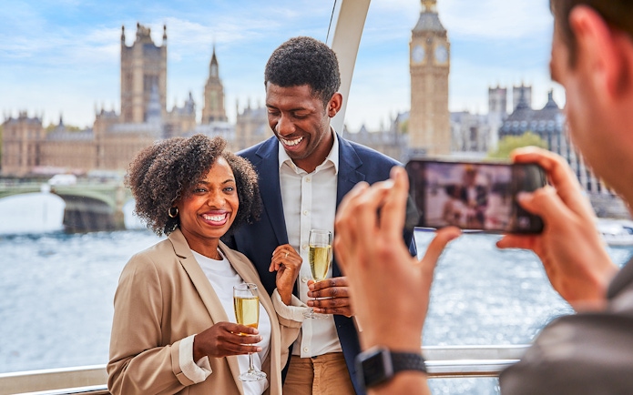 Couple enjoying champagne on the London Eye with Big Ben in the background.