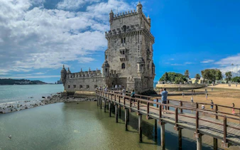 Belém Tower with visitors on a wooden walkway, Lisbon Full Day Tour.