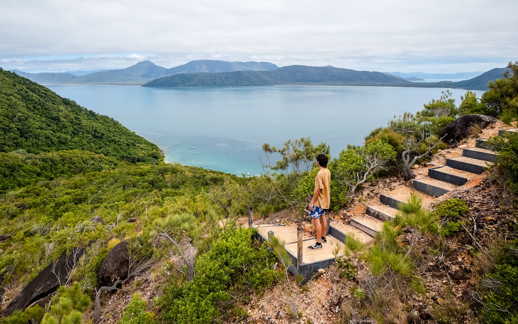 Person overlooking ocean and lush hills on Fitzroy Island adventure trail.