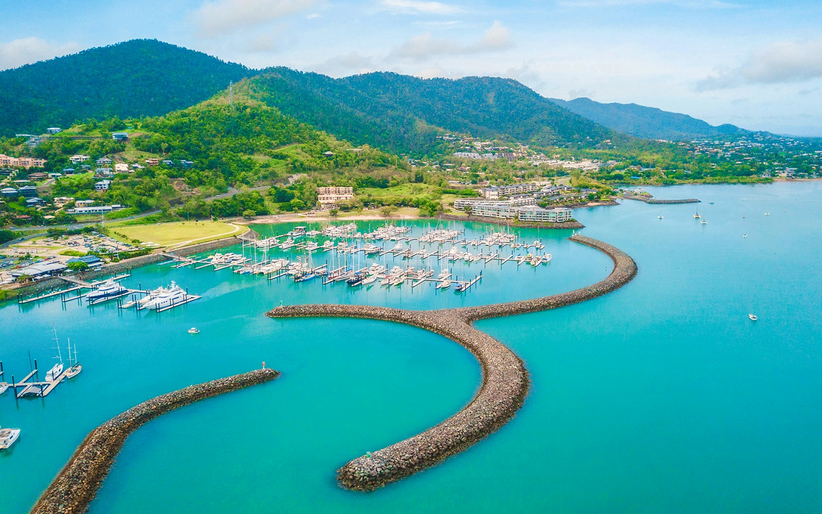 Coral Sea Marina with yachts and boats, surrounded by lush hills in Airlie Beach, Australia.