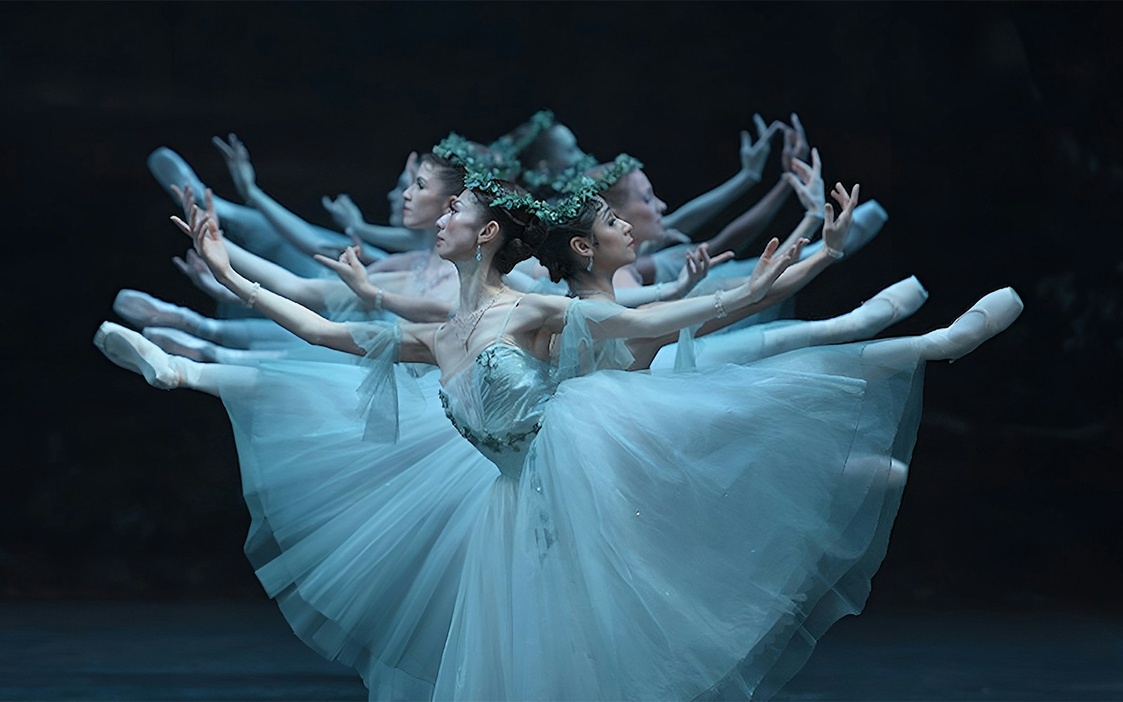 Ballet dancers performing "Giselle" in flowing white costumes on stage.