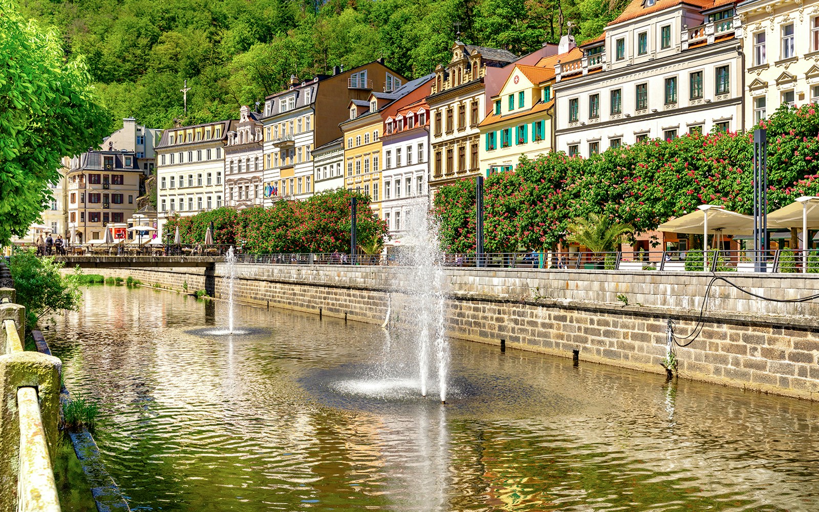 Karlovy Vary riverside with colorful buildings and fountains, Czech Republic.