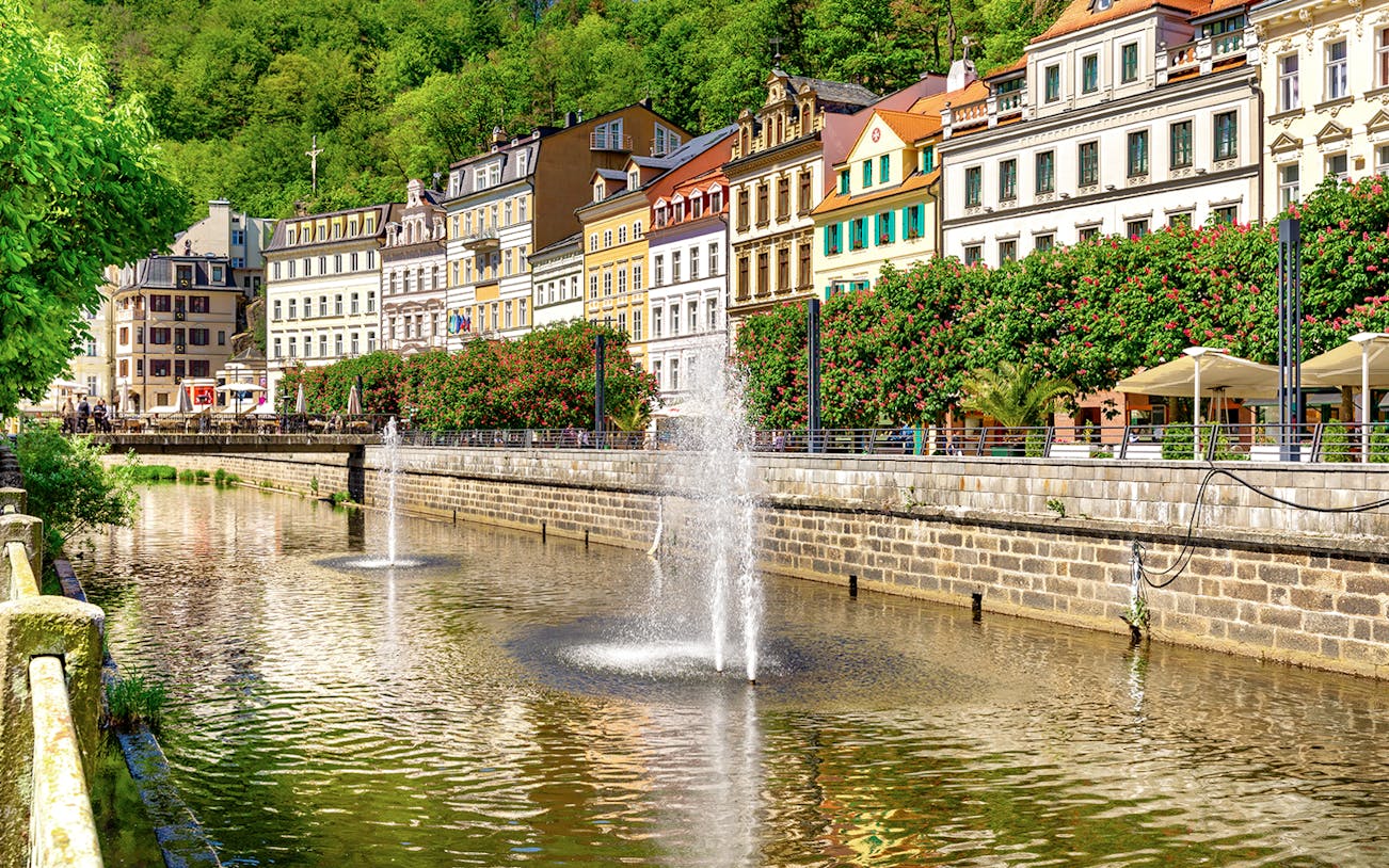 Karlovy Vary riverside with colorful buildings and fountains, Czech Republic.
