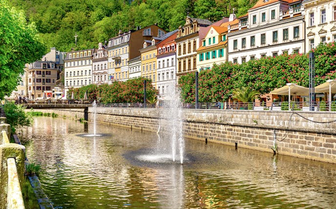 Karlovy Vary riverside with colorful buildings and fountains, Czech Republic.
