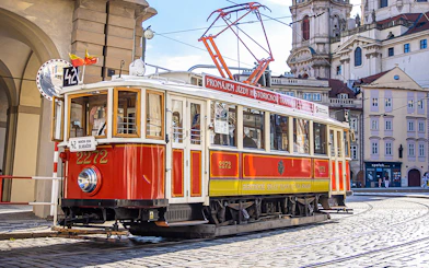 Historic red tram on cobblestone street during Prague hop-on hop-off tour.