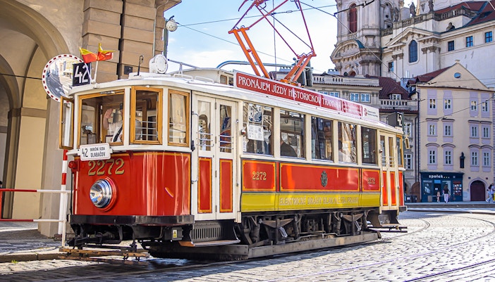 Historic red tram on cobblestone street during Prague hop-on hop-off tour.