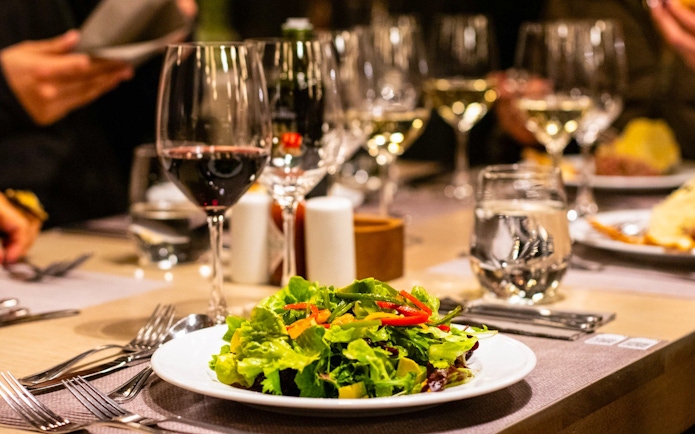 Salad and wine on table during Viña Concha y Toro Nighttime Dinner Show experience.