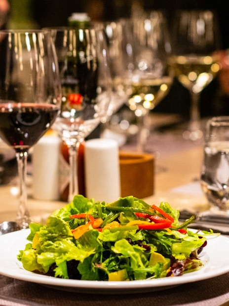 Salad and wine on table during Viña Concha y Toro Nighttime Dinner Show experience.