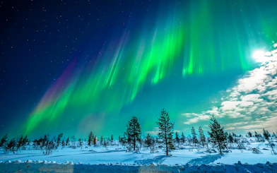 Northern Lights over snowy landscape in Tromso, Norway.