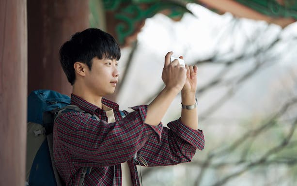 Traveler using smartphone in Korea with eSIM for unlimited data.