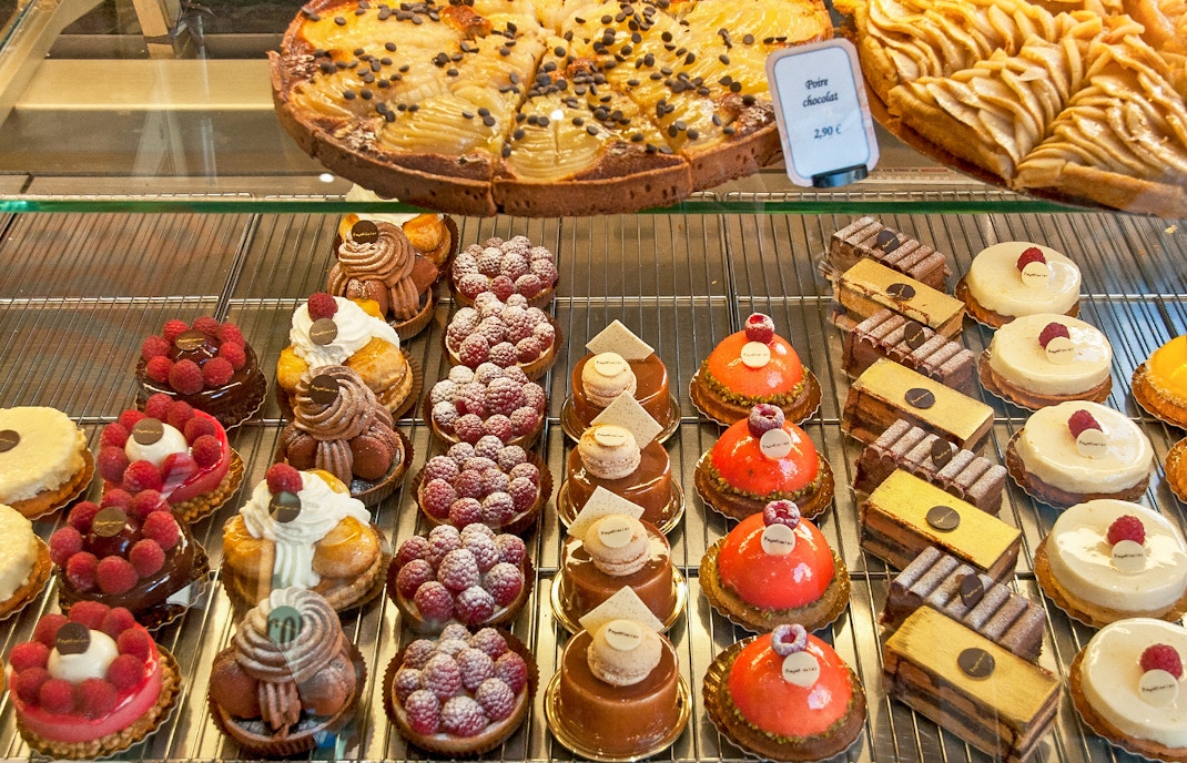 Assorted French pastries including tarts and cakes on display in a bakery.