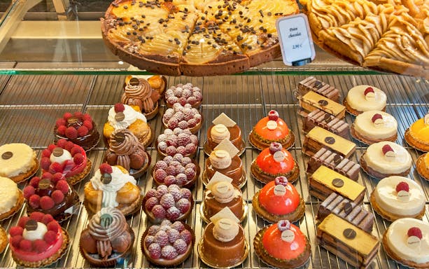 Assorted French pastries including tarts and cakes on display in a bakery.