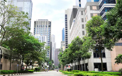Street view of modern skyscrapers and greenery in Singapore for self-guided city exploration game.