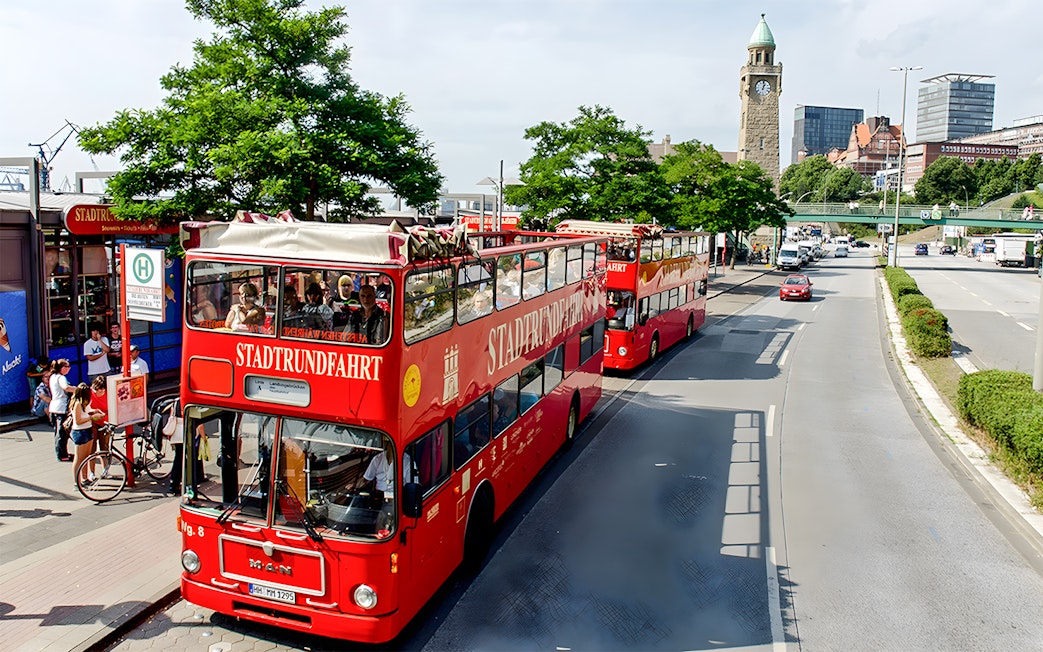 Red double-decker tour buses in Hamburg near St. Michael's Church, part of the Hamburg City Pass experience.
