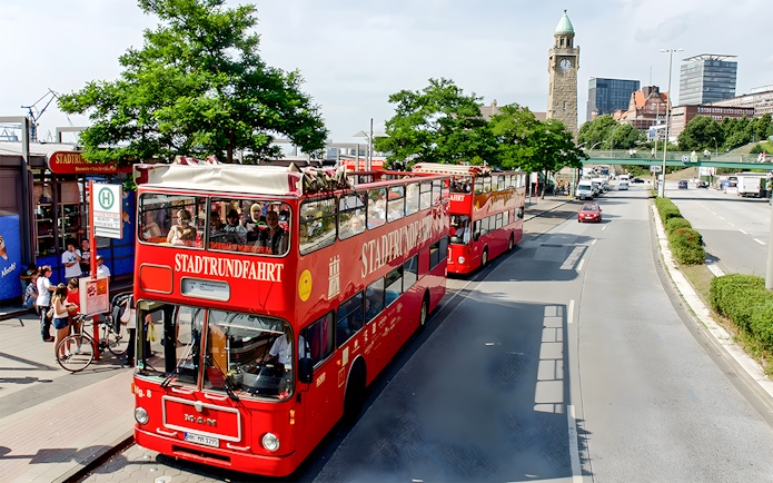 Red double-decker tour buses in Hamburg near St. Michael's Church, part of the Hamburg City Pass experience.