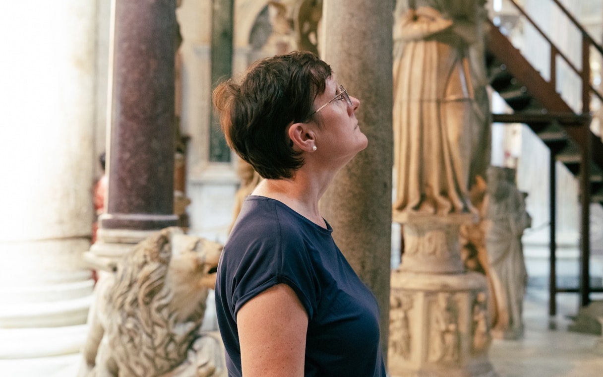 Woman observing sculptures inside Pisa Cathedral.