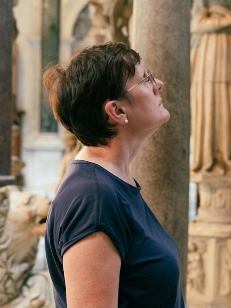 Woman observing sculptures inside Pisa Cathedral.